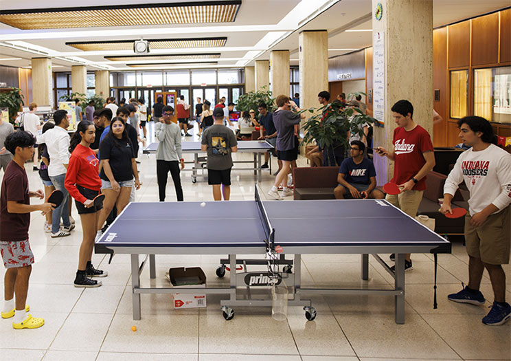 People playing ping pong in the lobby of Wells Library